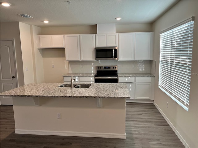 kitchen featuring decorative backsplash, stainless steel appliances, sink, a center island with sink, and white cabinets