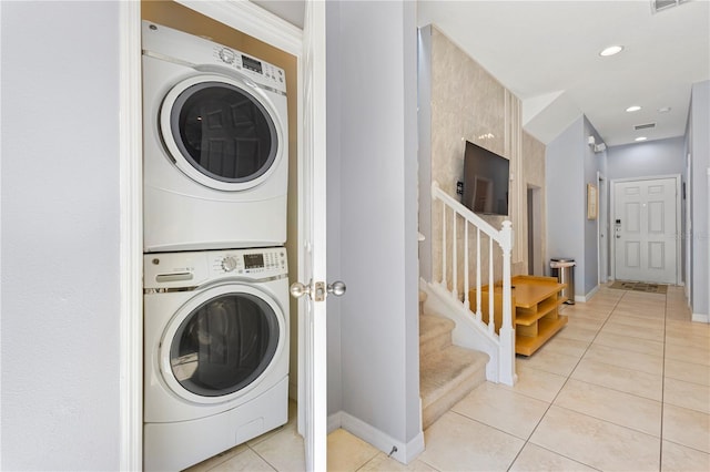 clothes washing area featuring stacked washer and dryer and light tile patterned flooring