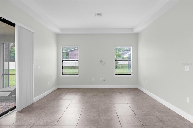 unfurnished room with a raised ceiling, a wealth of natural light, and light tile patterned floors