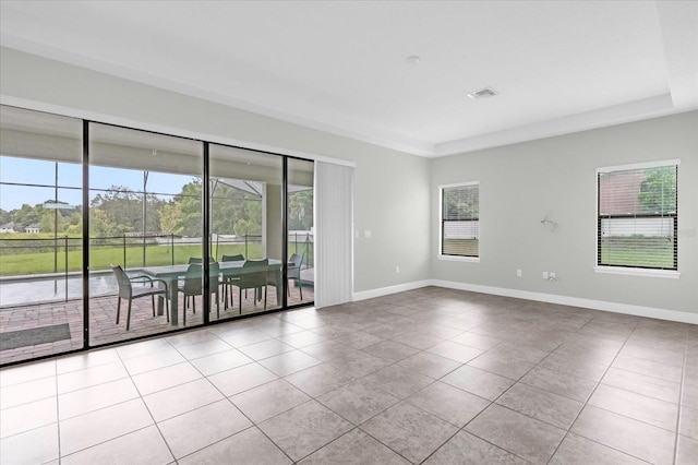 tiled empty room featuring a tray ceiling