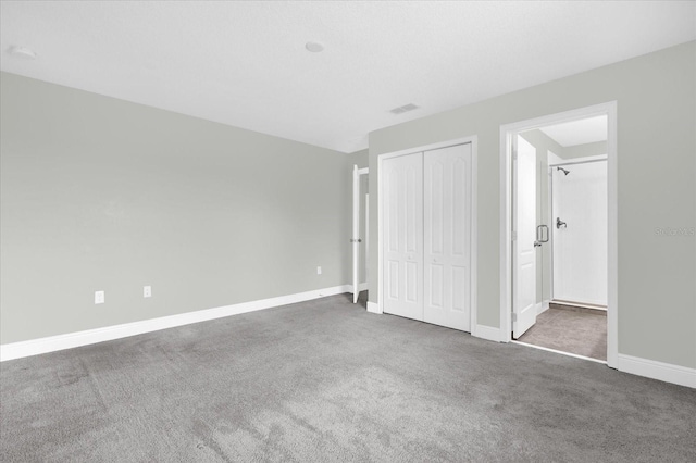 unfurnished bedroom with ensuite bathroom, carpet floors, and a closet