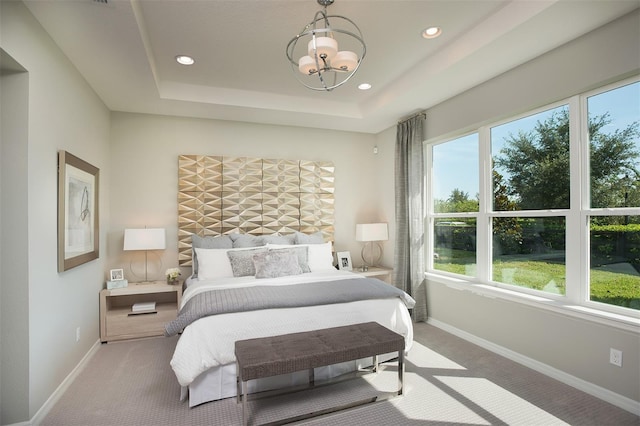 carpeted bedroom featuring a raised ceiling and a notable chandelier