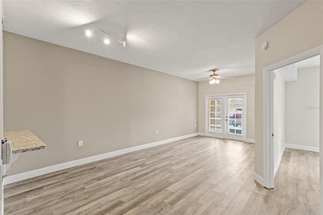 empty room featuring light hardwood / wood-style floors, ceiling fan, a textured ceiling, and rail lighting