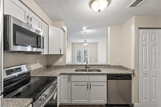 kitchen featuring sink, ceiling fan, appliances with stainless steel finishes, white cabinetry, and light stone countertops