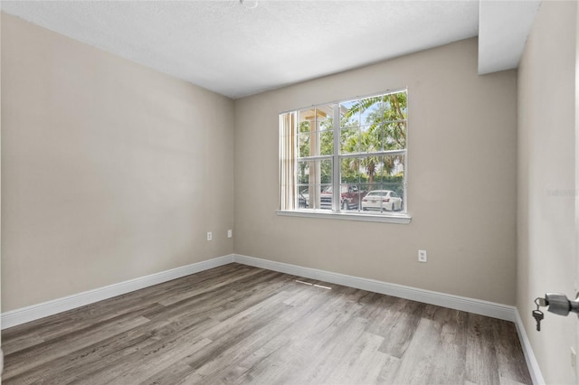 unfurnished room featuring light hardwood / wood-style flooring and a textured ceiling