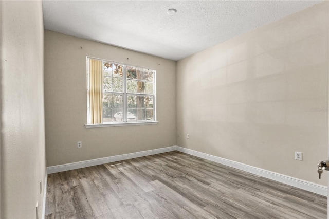 spare room featuring light hardwood / wood-style flooring and a textured ceiling