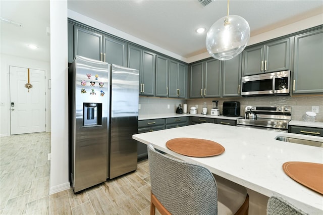 kitchen featuring hanging light fixtures, appliances with stainless steel finishes, and decorative backsplash