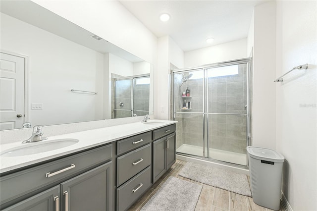 bathroom featuring a shower with door, vanity, and wood-type flooring