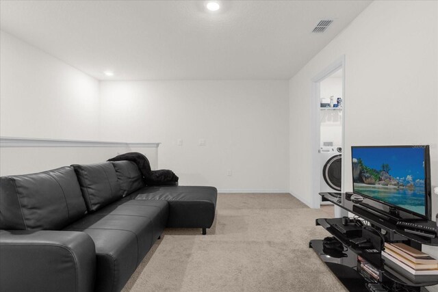 living area featuring light carpet, washer / dryer, baseboards, and visible vents