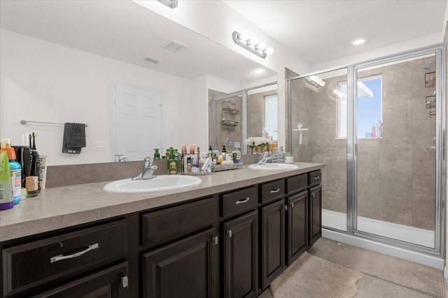 bathroom with double vanity, a stall shower, a sink, and tile patterned floors