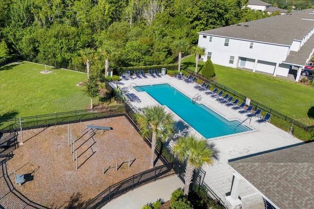 community pool with a patio, a lawn, and fence