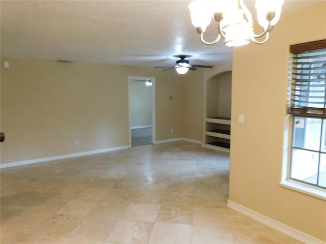 spare room featuring ceiling fan with notable chandelier and a wealth of natural light