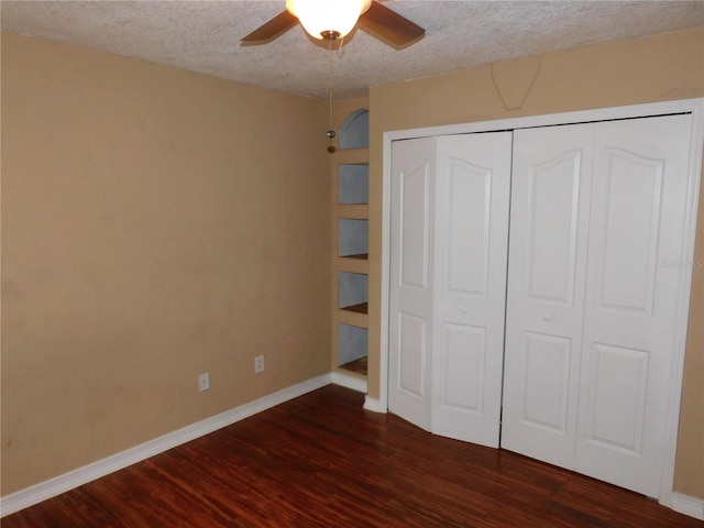 unfurnished bedroom featuring a textured ceiling, a closet, ceiling fan, and dark hardwood / wood-style flooring