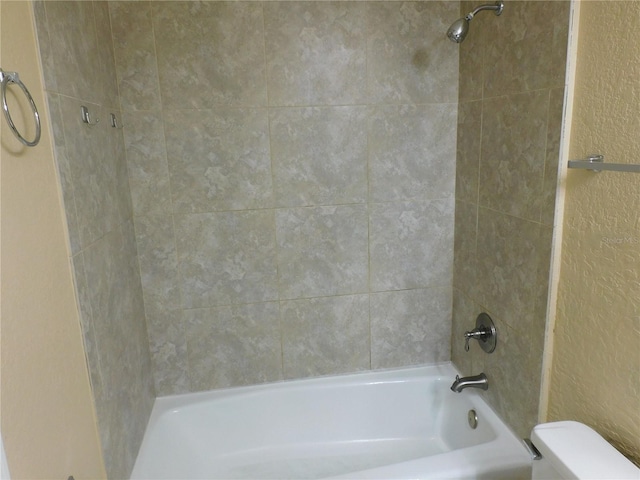 bathroom with tiled shower / bath combo and toilet