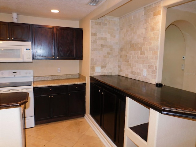 kitchen with white appliances, light tile patterned floors, dark brown cabinets, and a textured ceiling