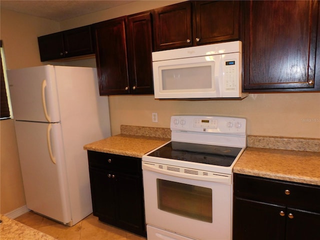 kitchen featuring white appliances, dark brown cabinetry, and light tile patterned floors