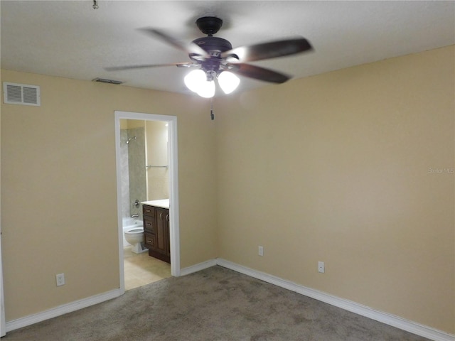 unfurnished bedroom featuring ceiling fan, light carpet, and ensuite bathroom