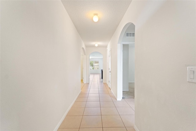 hall featuring a textured ceiling and light tile patterned floors