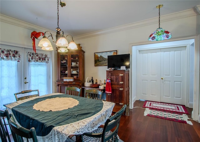 dining space with dark hardwood / wood-style floors, crown molding, and an inviting chandelier