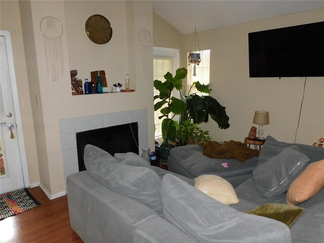 living room featuring lofted ceiling, dark wood-type flooring, and a tile fireplace