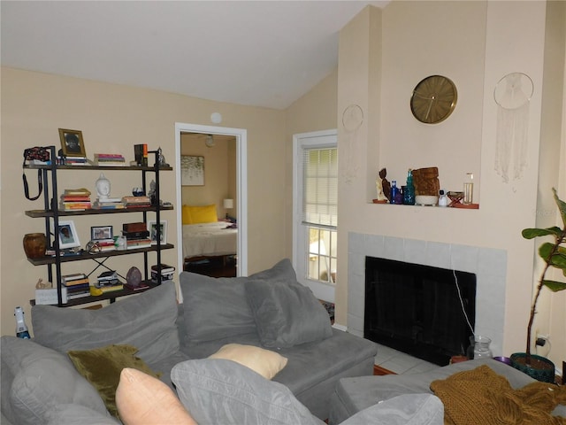 living room featuring a tiled fireplace and vaulted ceiling