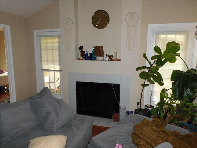 tiled living room featuring lofted ceiling and a tile fireplace