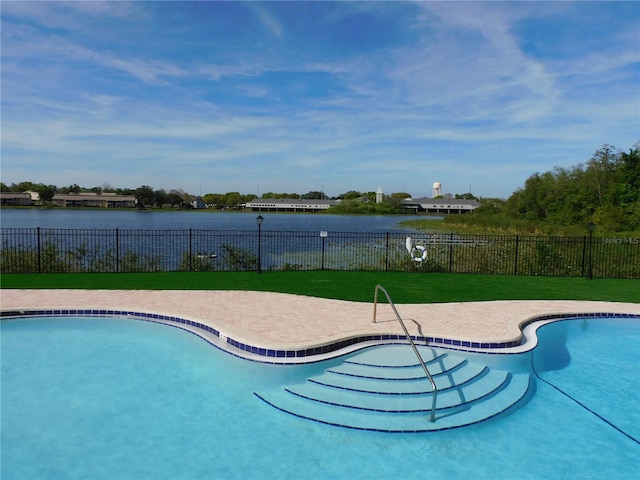 view of pool with a water view and a yard