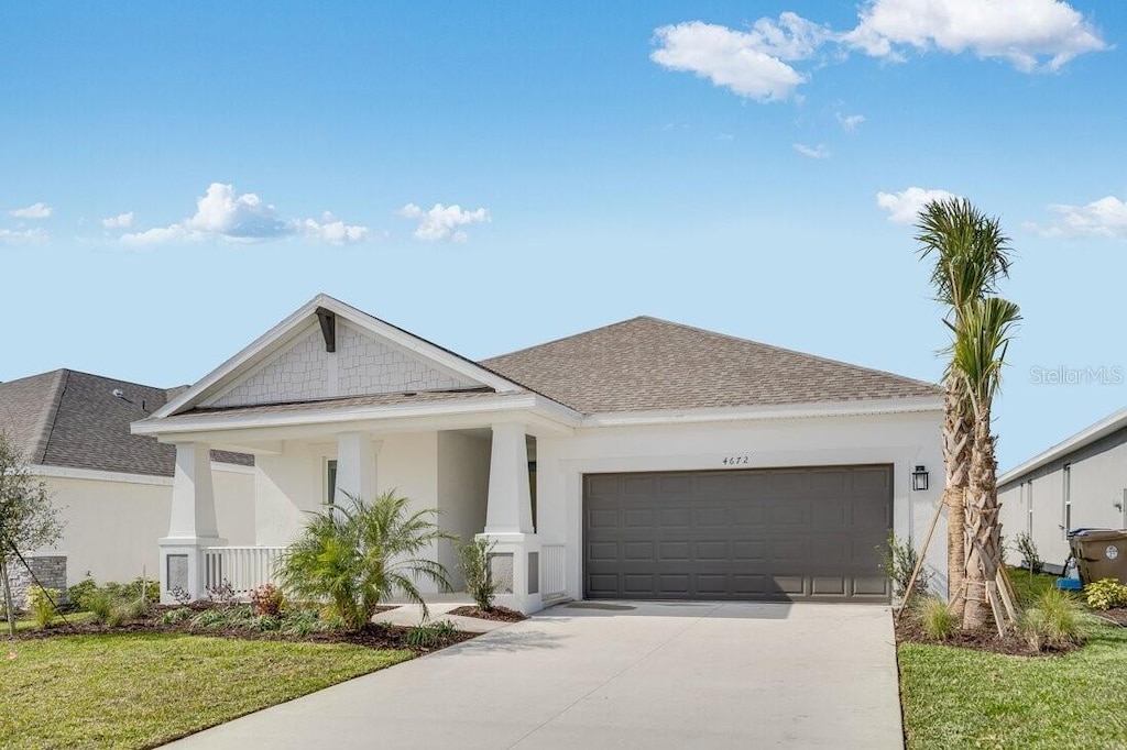 view of front of home with a garage, a front yard, and a porch