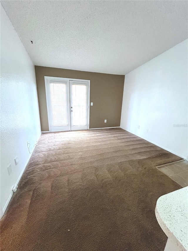 unfurnished room with carpet and a textured ceiling