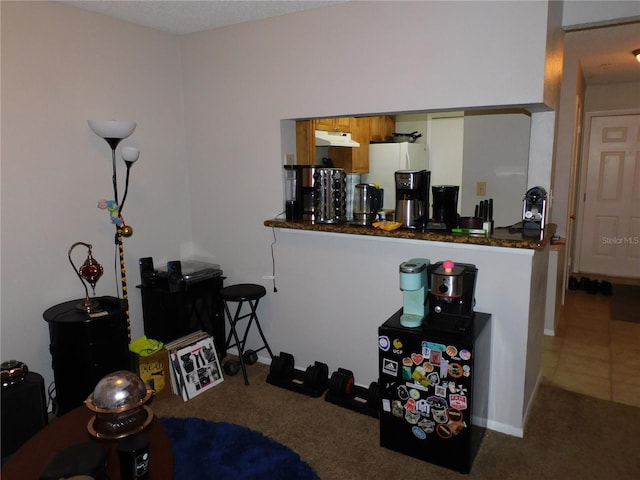 interior space with white fridge, white cabinets, carpet, kitchen peninsula, and dark stone counters