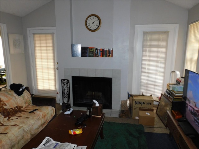 living room with lofted ceiling and a tiled fireplace