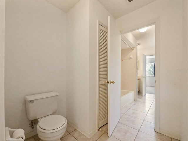 bathroom with tile patterned floors, a bath, and toilet