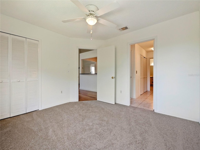 unfurnished bedroom featuring a closet, ceiling fan, and light colored carpet