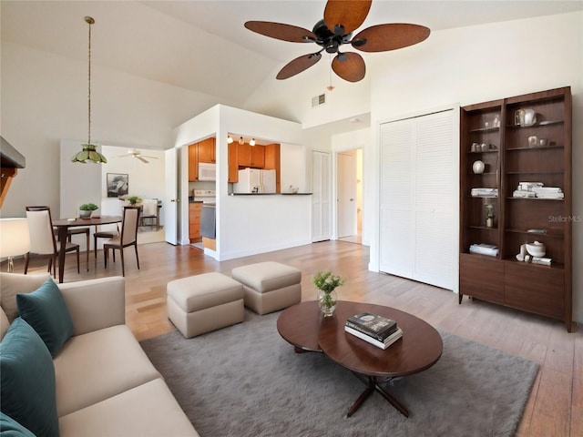 living room featuring ceiling fan, light wood-type flooring, and high vaulted ceiling