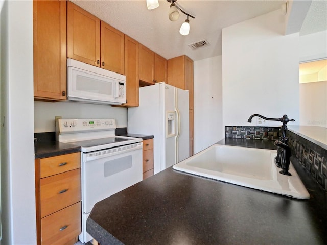 kitchen with sink, rail lighting, a textured ceiling, and white appliances