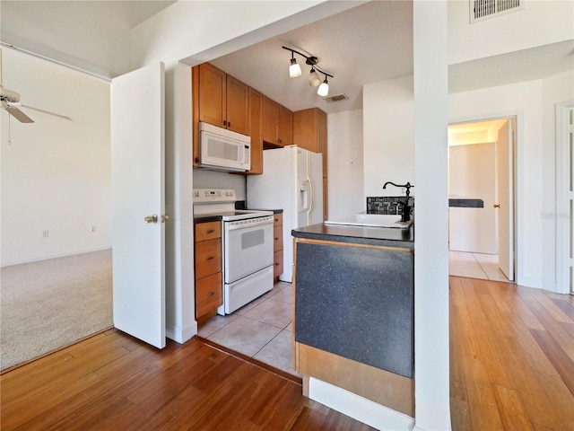 kitchen with ceiling fan, light carpet, sink, rail lighting, and white appliances