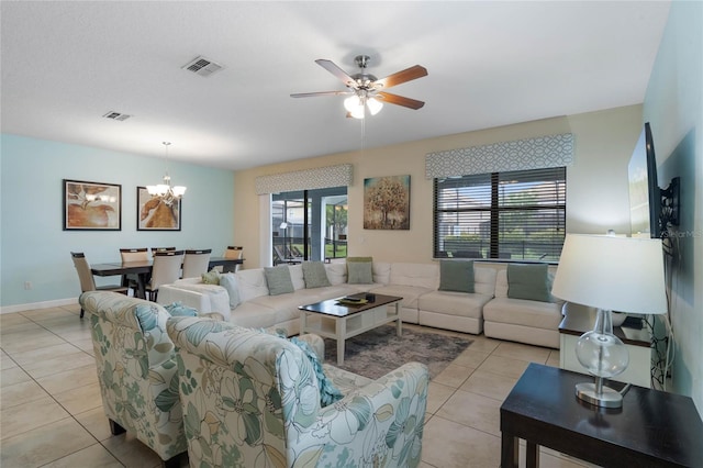 tiled living room with ceiling fan with notable chandelier