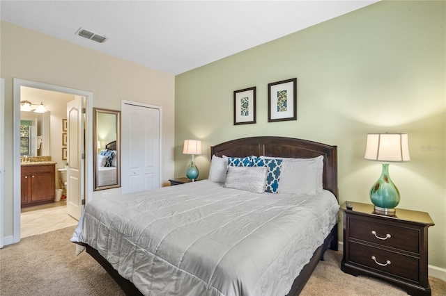 bedroom with light colored carpet, a closet, and connected bathroom