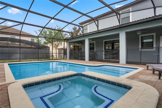 view of swimming pool featuring an in ground hot tub, glass enclosure, ceiling fan, and a patio area