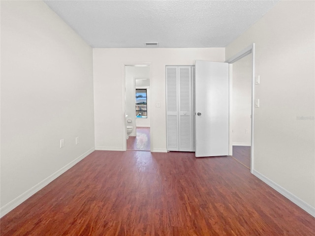 empty room featuring a textured ceiling and dark hardwood / wood-style floors