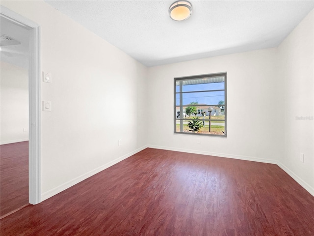 unfurnished room featuring dark hardwood / wood-style flooring and a textured ceiling