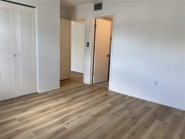 unfurnished bedroom with light hardwood / wood-style flooring and a closet