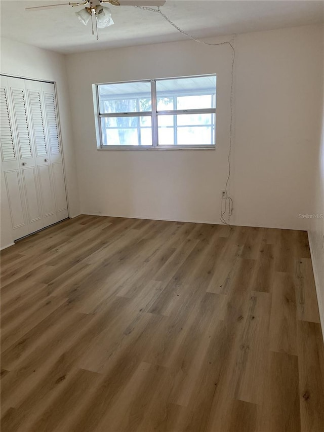 unfurnished bedroom featuring a closet, hardwood / wood-style flooring, and ceiling fan