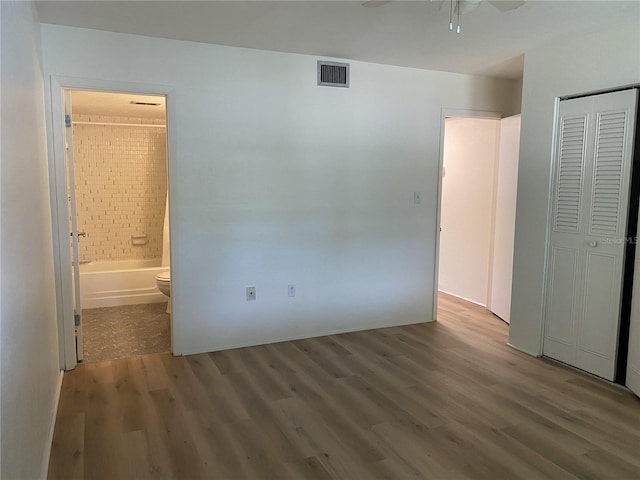 unfurnished bedroom with connected bathroom, ceiling fan, and dark hardwood / wood-style flooring