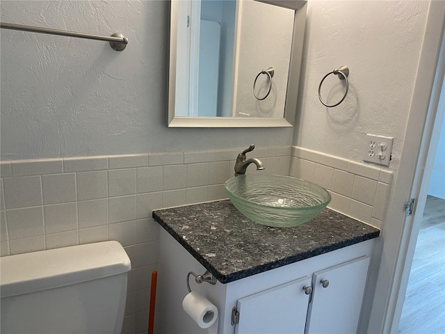 bathroom with vanity, tile walls, and toilet