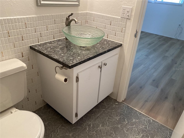 bathroom with vanity, tile walls, and toilet