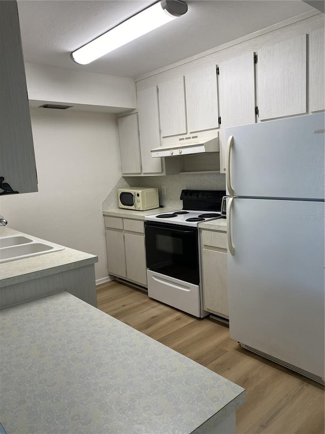 kitchen with white appliances, light hardwood / wood-style flooring, and sink