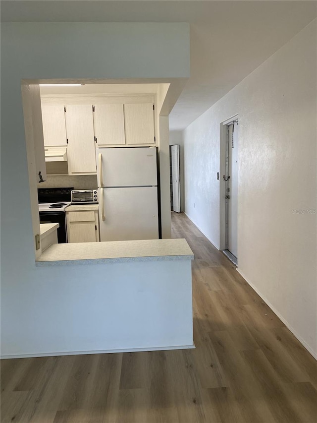 kitchen featuring kitchen peninsula, white appliances, and hardwood / wood-style flooring