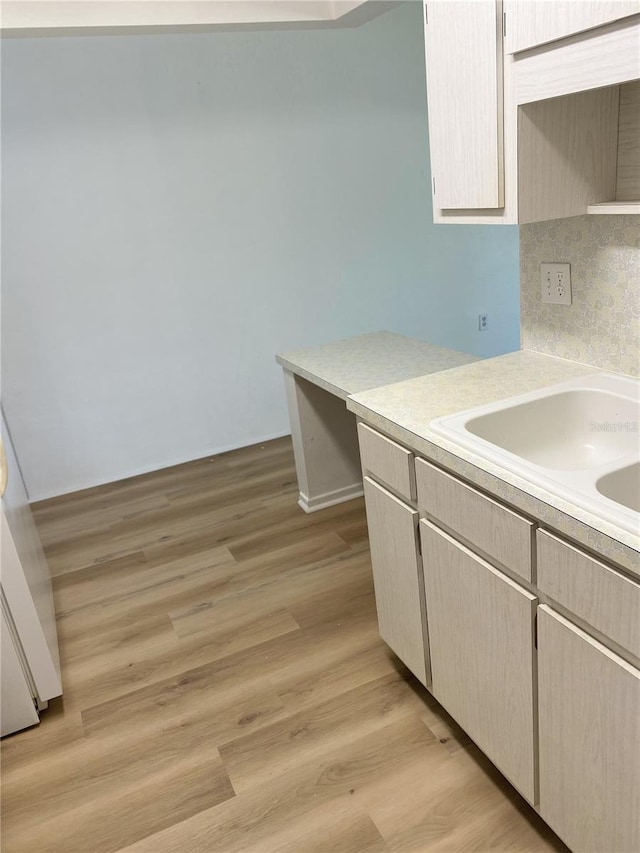 kitchen featuring tasteful backsplash, light brown cabinetry, sink, and light wood-type flooring