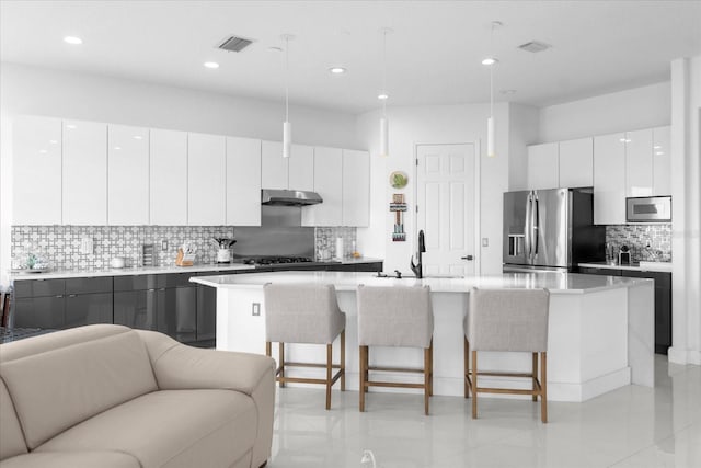 kitchen with a center island with sink, white cabinets, stainless steel appliances, and sink